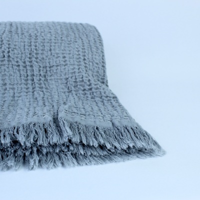 Cobertor cinzento claro com padrão texturizado e franjas nas extremidades