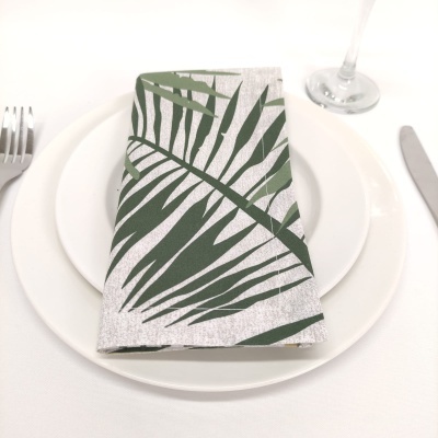 Guardanapo branco com folhas verdes sobre pratos brancos na mesa