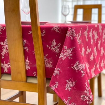 Mesa de madeira com toalha fúcsia estampada e cadeiras de madeira