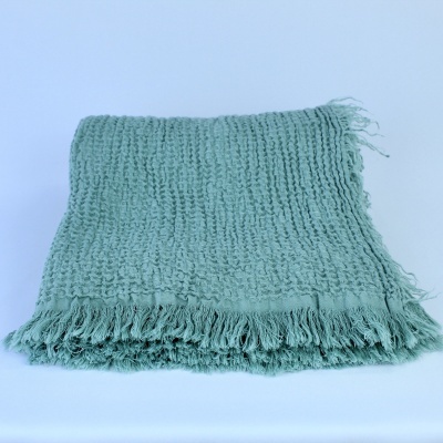 Manta verde-água com textura e franjas em fundo branco