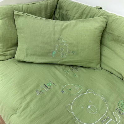Roupa de cama verde clara com bordados infantis e a palavra 'hello'