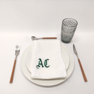 Conjunto de mesa com talheres de cabo de madeira, prato branco, guardanapo branco bordado e copo de vidro