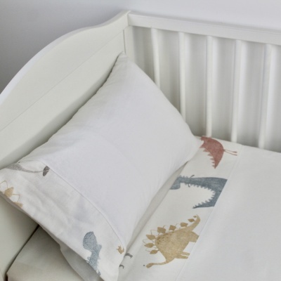 Berço branco com roupa de cama infantil com dinossauros coloridos