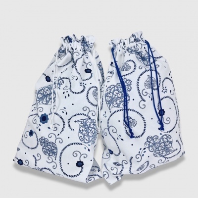 Duas bolsas de tecido branca com padrões azuis e cordões para fecho