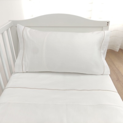 Cama branca para bebé com almofada e lençol brancos e detalhe castanho