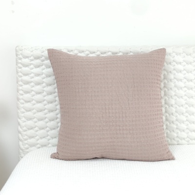 Almofada rosa claro com textura sobre cama branca acolchoada