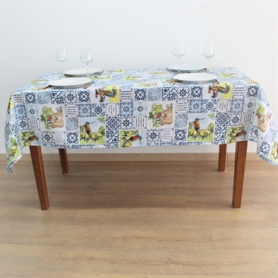 Toalha de mesa branca com padrão patchwork colorido com imagens e azulejos azuis numa mesa de madeira