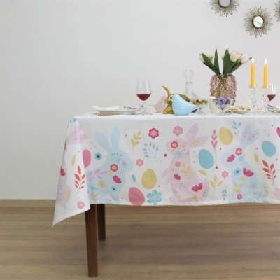 Toalha de mesa com padrão de coelhos, ovos coloridos e flores, mesa decorada com vinho, velas e flores
