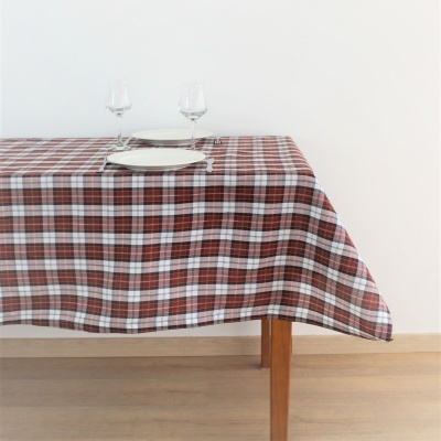 Toalha de mesa xadrez castanho e branco numa mesa de madeira com pratos e taças