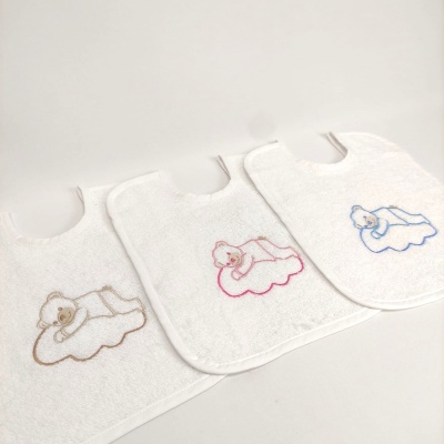 Três babetes brancos com ursinhos bordados em castanho, rosa e azul