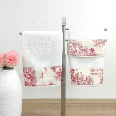 Conjunto de toalhas brancas com bordado vermelho penduradas em cabide metálico