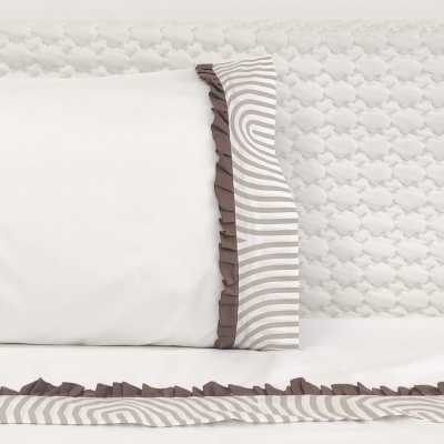 Jogo de cama com fronhas listradas bege e branco e bordas franzidas castanhas sobre tecido branco texturado.