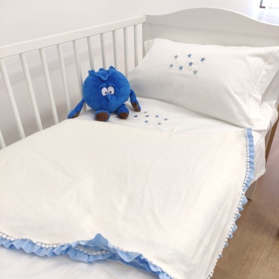 Cama de criança branca com roupa de cama branca e azul e peluche azul