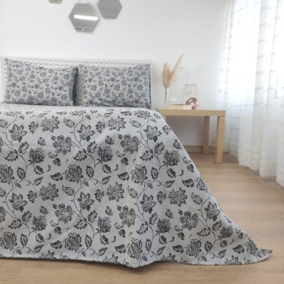 colcha cinza com padrão preto de folhas e almofadas em cama, mesa clara, decoração minimalista