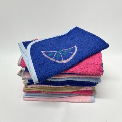 Conjunto de toalhas coloridas empilhadas com toalha azul bordada no topo