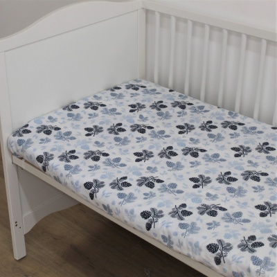 Cama de criança branca com colchão estampado com folhas azuis e pretas