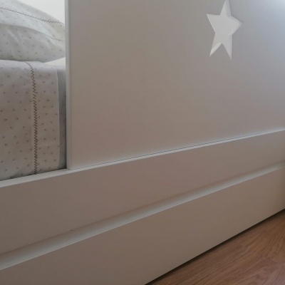 Cama infantil branca com cabeceira com estrela e roupa de cama com padrão de estrelas