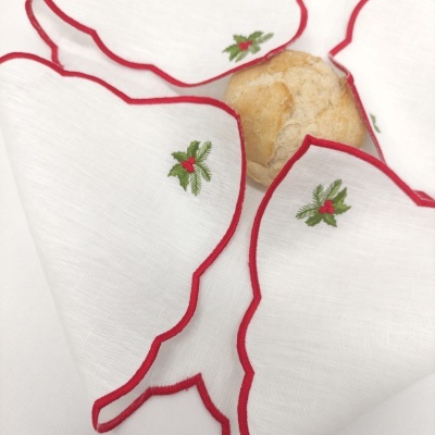Guardanapos brancos com bordas vermelhas e bordados de folhas verdes com frutos vermelhos