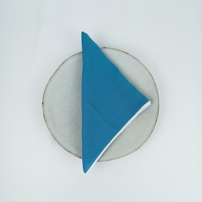 Prato cerâmico cinza claro com guardanapo azul em fundo branco