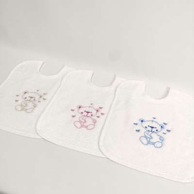 Três babetes brancos felpudos com ursos bordados em bege, rosa e azul
