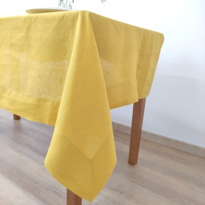 Toalha de mesa amarelo mostarda com padrão de losangos sobre mesa de madeira