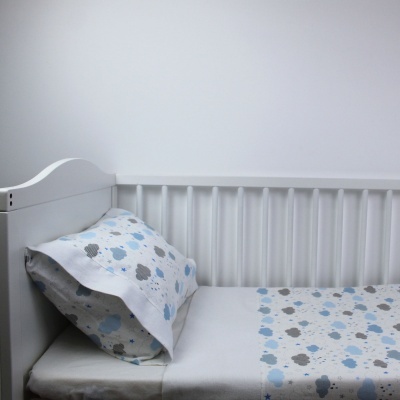 Berço branco com roupa de cama de padrão de nuvens azul e cinzento