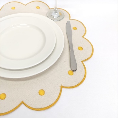 Pratos, faca e copo sobre jogo americano bege com pontos amarelos