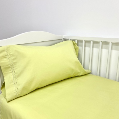 cama infantil branca com lençol e almofada verdes