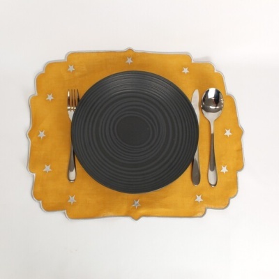 Conjunto de mesa com prato preto e talheres em guardanapo amarelo com estrelas
