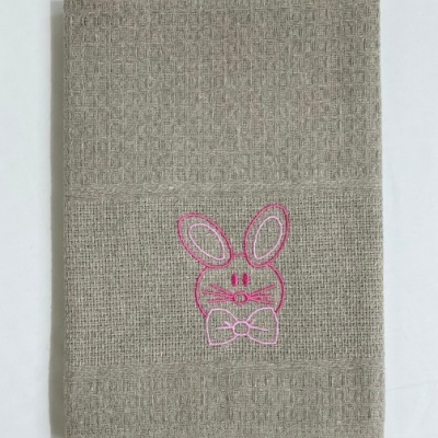 Toalha cinzenta com bordado rosa de coelho e laço.