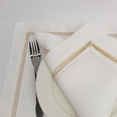 guardanapo e toalha de mesa brancos com bordado bege, prato branco e garfo de aço inoxidável