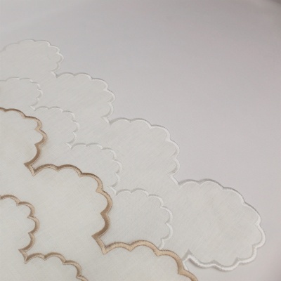 Tecido branco com bordados ondulados em branco e bege