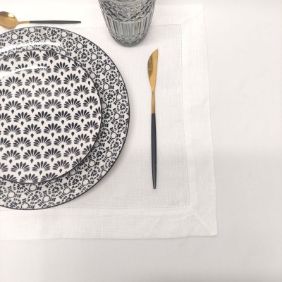 Conjunto de loiça com pratos, talheres dourados, copo de vidro e toalha branca