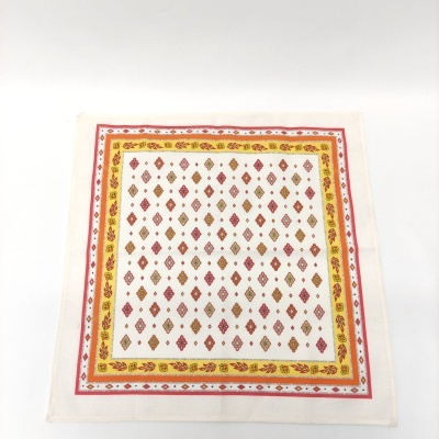 Pano de tecido branco com padrão de losangos e bordas coloridas.