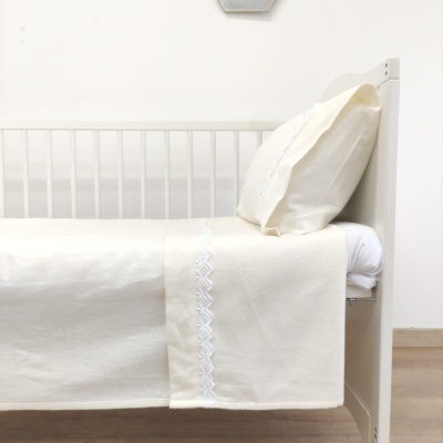 Cama branca com roupa de cama bege com renda branca