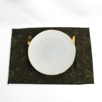 Conjunto de mesa com prato branco e talheres dourados sobre placemat preto com padrão dourado.