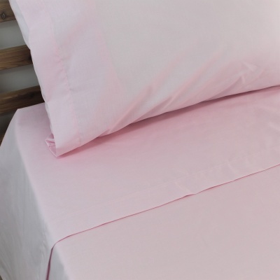 Jogo de cama cor-de-rosa liso com fronhas e lençol ajustado numa cama de madeira
