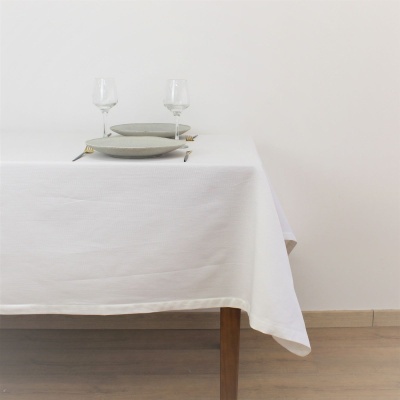 mesa com toalha branca, loiças cinzentas, garfos dourados, taças de vidro