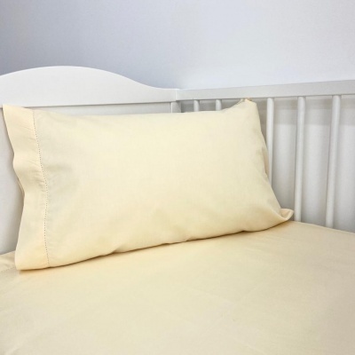 Almofada e lençol bege claro sobre estrado de madeira branca