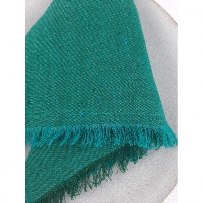 Tecido verde com franjas numa superfície clara