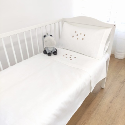 Cama infantil branca com roupa de cama branca bordada e peluche cinzento