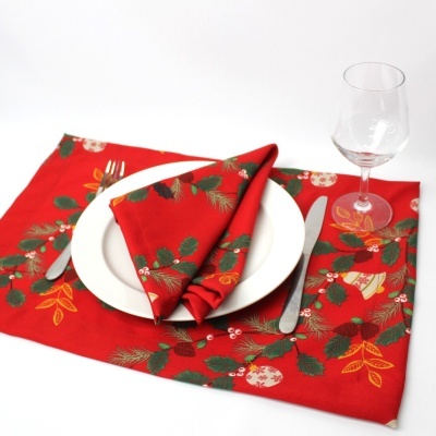 Conjunto de descanso de mesa e guardanapo vermelho com padrão natalício, prato branco, talheres e copo de vidro