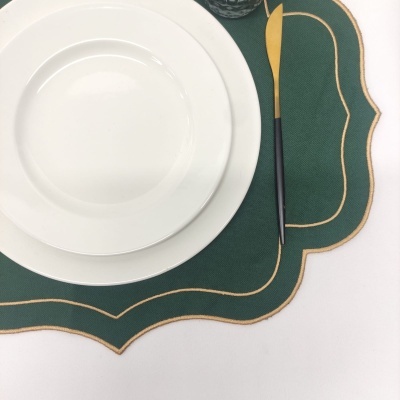 Pratos brancos sobre individual verde com bordas douradas e faca dourada