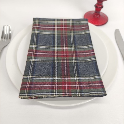 Guardanapo xadrez azul e vermelho sobre prato branco com talheres e copo vermelho