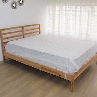 Cama de madeira clara com colchão e lençol branco com padrão cinza