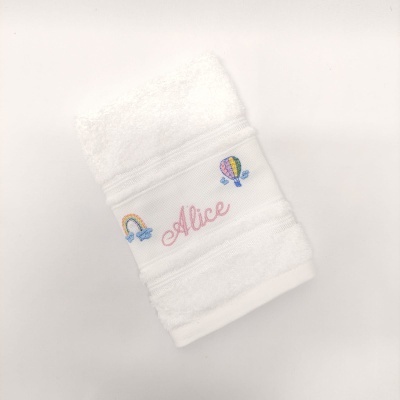 Toalha branca bordada com o nome Alice e desenhos de balão e arco-íris