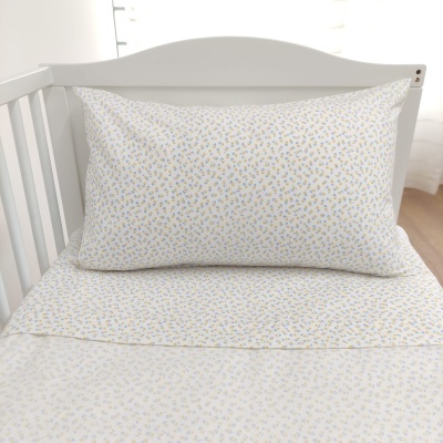 Lençóis com padrão de pequenas flores amarelas e azuis numa cama branca