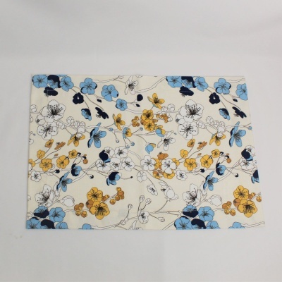 Toalha rectangular com padrão floral azul, amarelo e preto sobre fundo bege