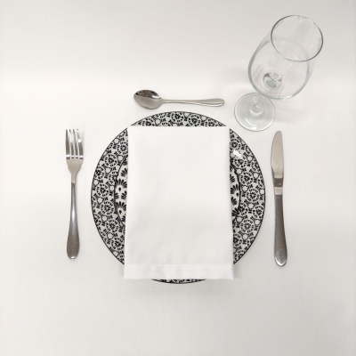 Conjunto de talheres e prato com padrão floral preto e branco com guardanapo branco e copo de vidro