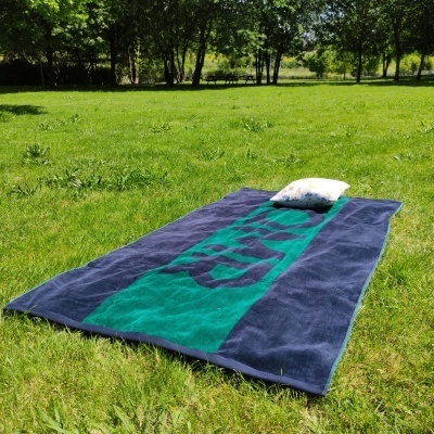 Toalha de praia azul e verde com almofada em relvado